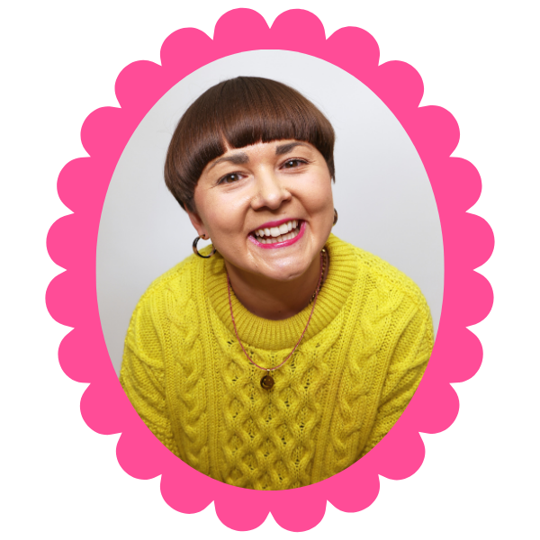 Beth, a woman with short brown hair, smiles widely. She is wearing a yellow jumper.