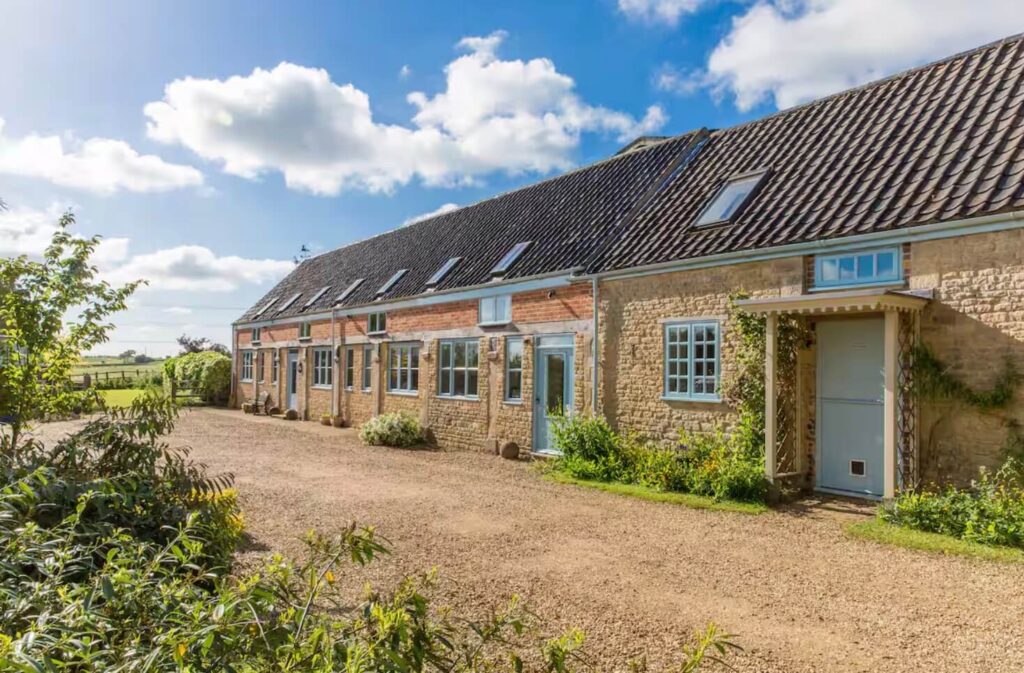 A long farmhouse building with light blue window frames and doors